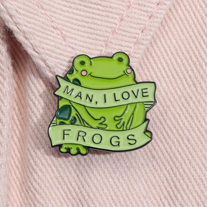 Cartoon green frog enamel pin with MILF letter banner on pink denim background