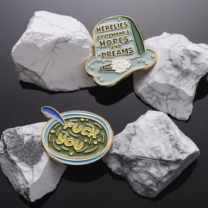 Gothic tombstone and green bowl enamel pins set on white stone with reflection