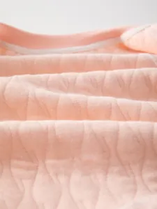 Détail du tissu en coton matelassé rose avec motifs de vagues pour barboteuse bébé