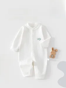Close-up of baby white cotton romper with cartoon mushroom embroidery and snap buttons