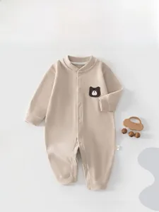 Detail of baby romper featuring soft ribbed fabric and a cute brown bear patch