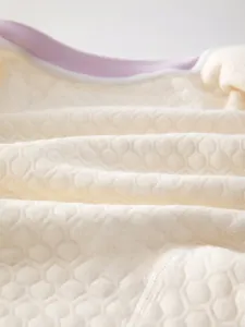 Vue macro de la texture alvéolée et du bord violet sur la barboteuse en coton pour bébé
