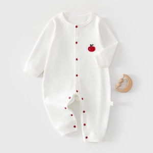 Detail of long sleeve baby cotton romper featuring red snaps and small apple embroidery