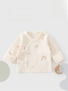 Flat lay of cotton newborn kimono wrap with rainbow prints and a wooden cat rattle