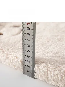 Detail view measuring the 25mm thickness of soft cream white fleece infant romper fabric