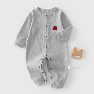 Detail of grey cotton baby romper with red snap buttons and apple patch embroidery
