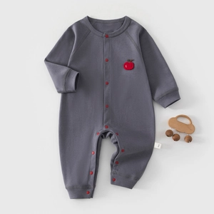 Detailed macro shot of infant grey cotton bodysuit with red buttons and apple embroidery