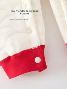 Detail view of eco-friendly resin snaps on quilted baby romper with ribbed red cuffs