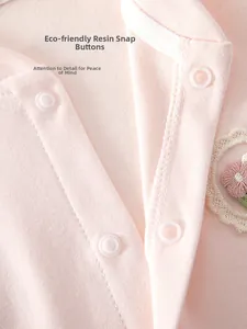 Makroaufnahme der umweltfreundlichen Druckknöpfe und Stickereien am Baby-Einteiler aus Baumwolle