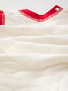 Close-up of quilted baby romper fabric with red trim and soft breathable cotton texture