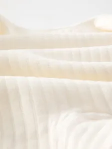 Close-up of baby romper fabric with breathable vertical knit texture in cream white