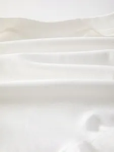 Close-up of soft white cotton fabric showing breathable knit texture for baby onesies