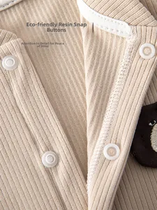 Detail of eco-friendly resin snap buttons on baby romper with ribbed knit fabric texture