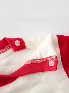 Detail of red quilted baby bodysuit showing neck snap buttons and fabric texture