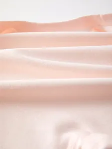 Nahaufnahme von weichem rosa Baby-Body-Stoff mit Baumwollstruktur und Strickmuster