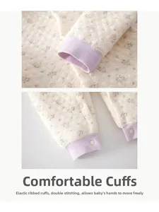 Détail d'une barboteuse matelassée pour bébé avec imprimé floral et poignets côtelés mauves