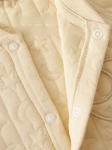 Detail of baby quilted cotton romper showing eco-friendly resin snap buttons and moon texture