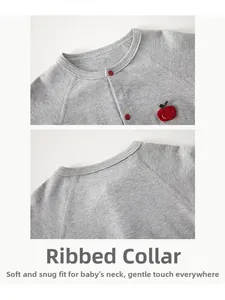 Detail of baby cotton bodysuit neckline with red snap buttons and apple embroidery