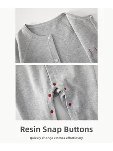 Detail of grey knitted baby romper featuring white resin snap buttons and red crotch snaps