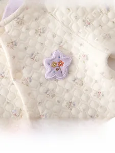 Détail d'une barboteuse matelassée en coton pour bébé avec motifs floraux et broderie fleur