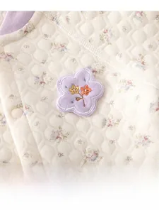 Macro detail of quilted cotton fabric with purple floral prints and applique embroidery