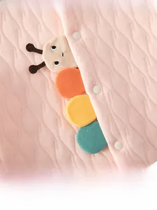 Détail d'une barboteuse matelassée rose pour bébé avec broderie de chenille colorée en peluche
