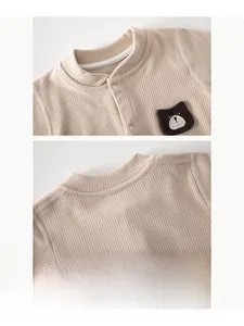 Detail of baby beige knit romper featuring a soft round neck and cute brown bear embroidery