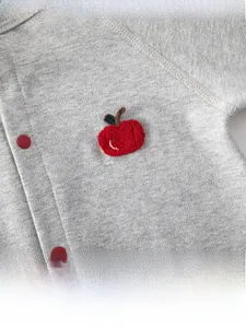 Close-up of grey cotton baby bodysuit with red apple embroidery and snap buttons