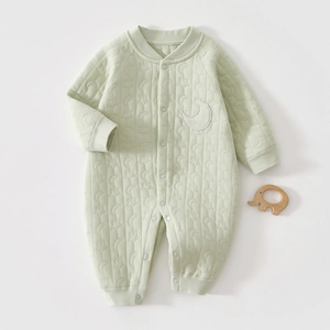 Detail of baby quilted romper with moon and star texture and embroidered baby patch