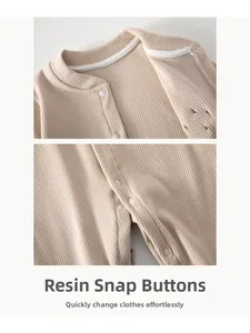 Detail view of resin snap buttons on beige ribbed knitted baby romper fabric