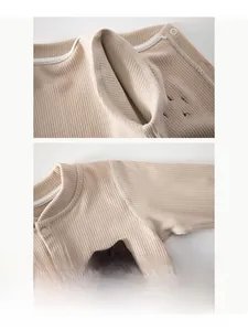 Detail of flat-lock seams and bear patch on beige ribbed cotton baby bodysuit