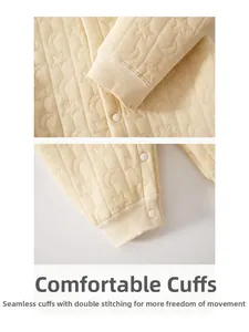 Detail of star-patterned quilted baby romper showing ribbed cuffs and snap buttons