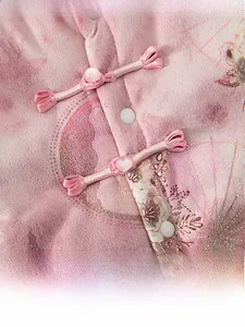 Detail of pink Chinese-style baby coat with traditional floral prints and pearl button knots