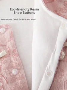 Détail du tissu jacquard rose avec boutons-pression en résine écologique sur gilet bébé