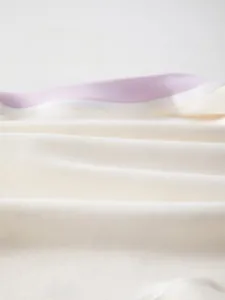 Détail du tissu en coton doux pour body bébé avec texture fine et liseré violet