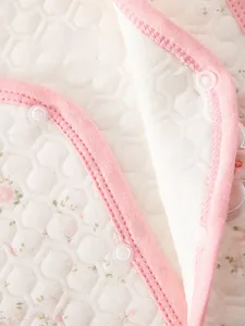 Detail of eco-friendly resin snap buttons on quilted floral cotton baby vest fabric