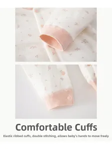 Détail d'un barboteuse pour bébé avec bords-côtes roses et boutons-pression sur coton fleuri