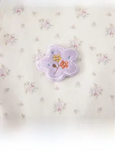 Détail de la barboteuse en coton pour bébé avec imprimé fleuri et broderie d'étoile