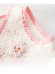 Close-up of baby vest featuring hexagonal quilting, floral prints and soft pink piping
