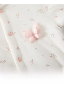Détail macro d'un barboteuse pour bébé avec motif floral, papillon 3D et boutons roses