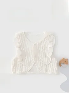 Gros plan sur un gilet en tricot blanc pour bébé avec volants et texture torsadée