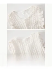 Détail du gilet en tricot blanc pour bébé avec motifs torsadés et volants aux manches