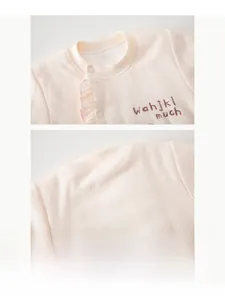 Detail of baby romper neckline with ruffle trim, embroidery, and white snap buttons