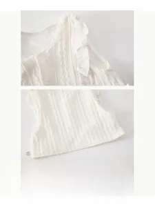 Gros plan sur le gilet tricoté blanc pour bébé avec maille torsadée et détails de volants