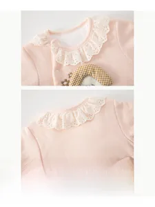 Dettaglio della tutina lavorata a maglia rosa per neonata con colletto in pizzo bianco fine
