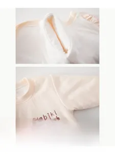 Detail of baby cotton onesie featuring ruffle collar and soft embroidered lettering