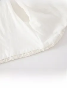 Gros plan d'un gilet en coton blanc pour bébé avec coutures plates et bord en dentelle
