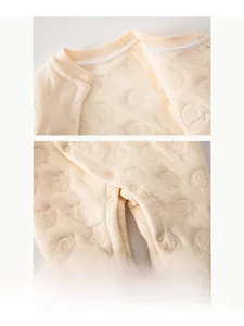 Close-up of resin snap buttons on cream baby quilted romper with elephant pattern