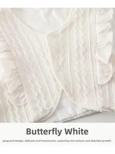 Détail du gilet en tricot blanc avec motifs jacquard et volants pour bébé fille