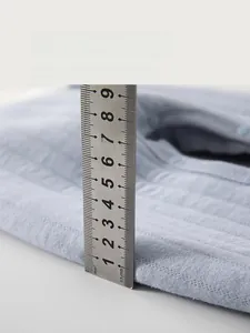 Detail showing the 1cm thickness of the light blue quilted cotton baby pants with a ruler